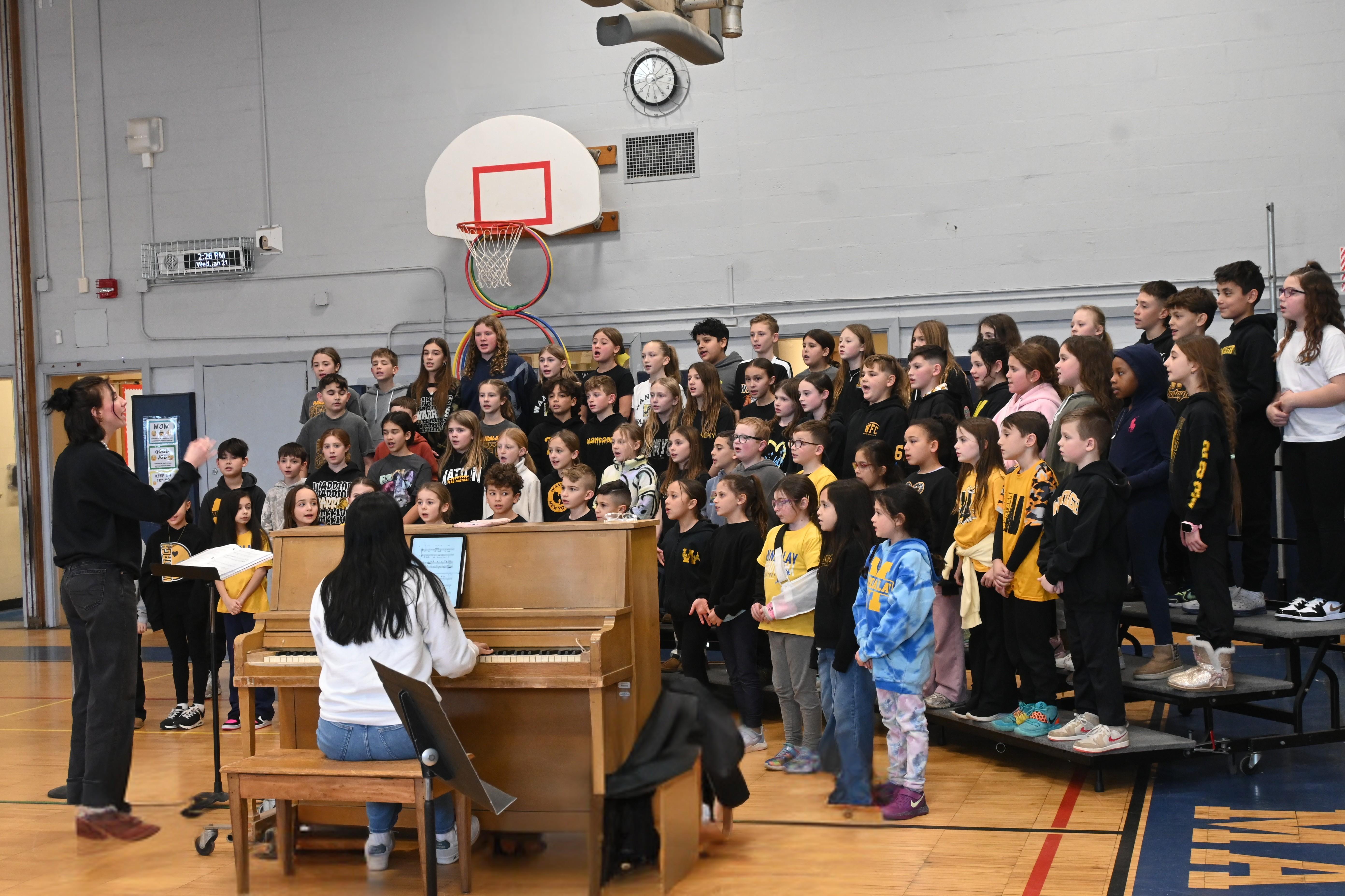 kids standing on risers singing in front of piano